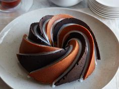 there is a chocolate cake with orange and brown icing on the plate, ready to be eaten