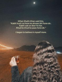 a woman standing in the middle of a desert holding a glass of wine at night