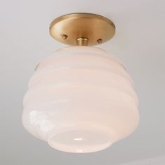 a light fixture with a white glass shade hanging from it's center point on the ceiling