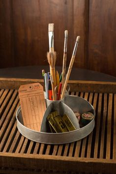 a cup filled with pens and pencils on top of a wooden table