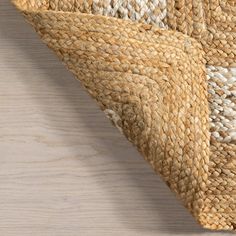 an area rug with white and beige colors on top of a wooden floor next to a wall