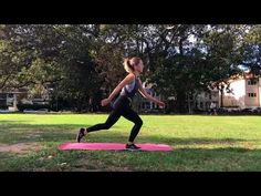 a woman is running on a pink mat in the park with trees and buildings behind her