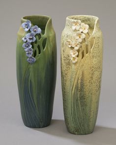 two vases with flowers on them sitting next to each other