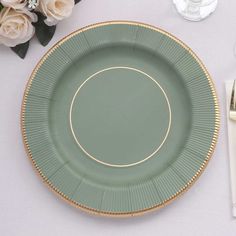 a green plate sitting on top of a white table next to silver utensils