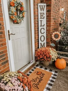 a welcome mat with flowers and pumpkins on the front porch