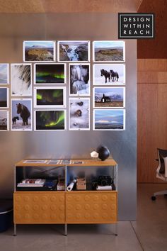 a wall with pictures on it and a chair in front of the sideboard is shown