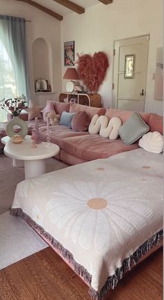 a living room filled with lots of pink furniture and pillows on top of a bed