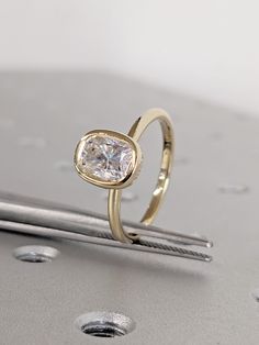 a diamond ring sitting on top of a metal table next to some screwdrivers