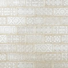 a white tile wall with an intricate design on it