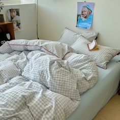 an unmade bed in a bedroom with pictures on the wall