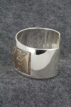 This vintage sterling silver & 14k gold fill bracelet was made by Navajo silversmith Dan Jackson. The back is signed Jackson and stamped 14k.Size: 5 3/8" (will fit a 6 1/2" wrist)Gap: 1 1/8"Length: 1 3/8"Free shipping on all orders! We ship with USPS and always include tracking. All orders ship within a day of payment.Returns are accepted up to 30 days after you receive your order. Just send us a message. Our shop offers cash back or store credit. The item must be returned in new condition. Elegant Wide Band Stamped Jewelry, Traditional Silver Wide Band Jewelry, Silver Etched Wide Band Jewelry, Silver Wide Band Etched Jewelry, Collectible Wide Band Engraved Jewelry, Collectible Engraved Wide Band Jewelry, Silver Southwestern Style Cuff Bracelet For Formal Occasions, Traditional Gold-colored Sterling Silver Bracelet, Traditional Gold Sterling Silver Bracelet