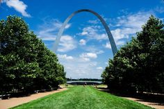 the gateway arch in st louis, missouri is surrounded by lush green grass and trees