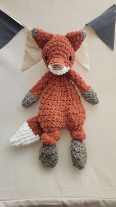 a crocheted fox stuffed animal sitting on top of a white cloth covered table