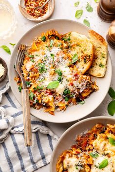 two plates of pasta and bread on a table