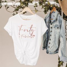 a white t - shirt with the words forty fabulous on it next to a denim jacket and hat