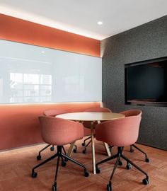 two pink chairs sitting at a round table in front of a flat screen tv