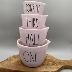 four pink bowls with words written on them sitting on a wooden stand next to a clock