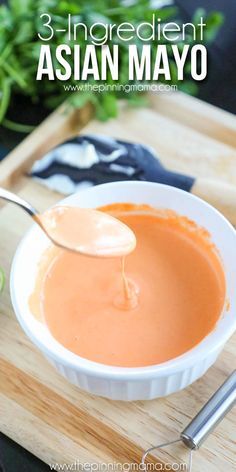 a spoon full of sauce on top of a wooden cutting board