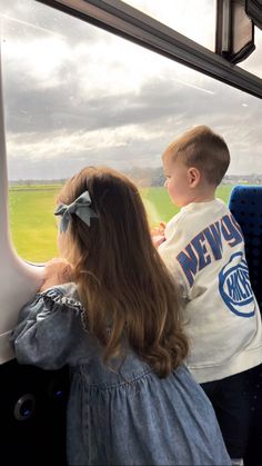 two children looking out the window on a train