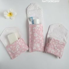 three small pink and white bags with flowers on them next to a flowery towel