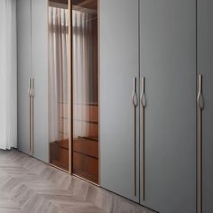 an empty room with wooden flooring and gray cupboards on the wall next to a window