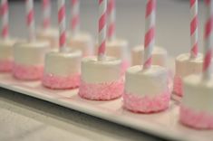 small marshmallows with pink and white icing are lined up on a plate