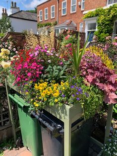 a green trash can filled with lots of flowers