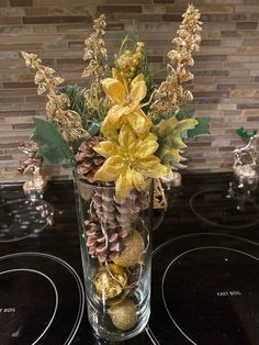 a glass vase filled with flowers and pine cones on top of a stove burner