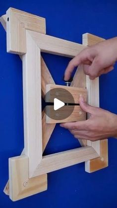 two hands are working on a wooden frame