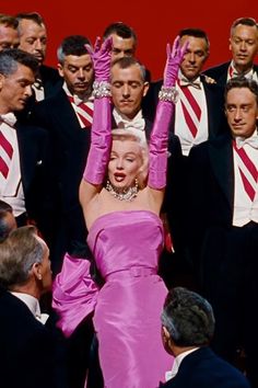 marilyn monroe in pink dress surrounded by men