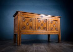 an old wooden chest with carvings on the front and sides, against a blue wall