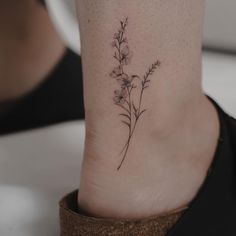 a small flower tattoo on the ankle that is sitting on a woman's foot