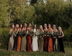 a group of women standing next to each other in front of some trees and bushes