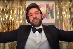 a man wearing headphones and bow tie standing in front of gold foiled curtains