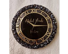 a black and gold clock with writing on the face that says, abuul adel hiba