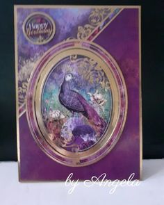 a purple and gold card with a peacock on it's front, surrounded by flowers