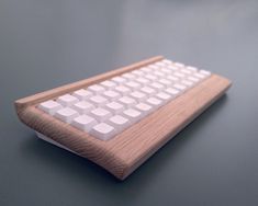 a wooden and white computer keyboard on a gray surface with one key board facing the camera