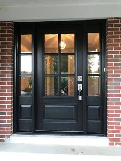 a black double door with two sidelights and glass panels on the front of a brick building