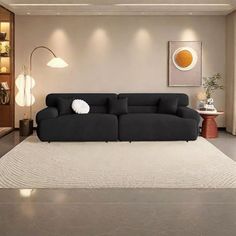 a black couch sitting on top of a rug in a living room next to a lamp