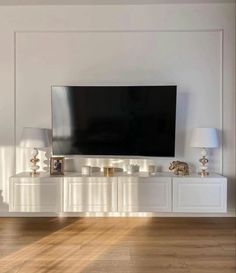 a large flat screen tv sitting on top of a white entertainment center