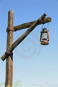 an old fashioned lantern hanging from a wooden pole