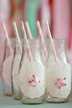 four mason jars with pink and white paper straws in them, lined up on a table