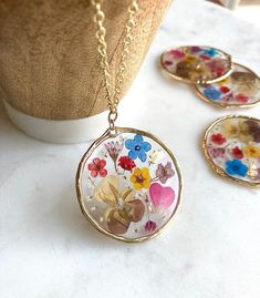 three necklaces with flowers on them sitting next to a vase