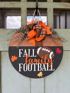 a sign that says fall family football hanging on a door with leaves and pumpkins