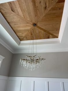 a chandelier hanging from the ceiling in a room with white walls and wood paneling