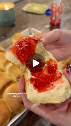 a person holding a piece of bread with jelly on it