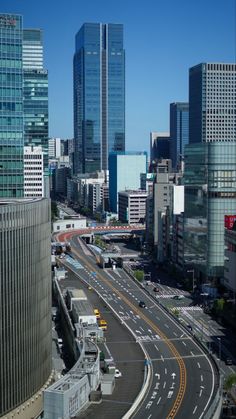 an aerial view of a city with skyscrapers and cars driving down the road in front of them