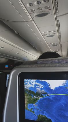 the inside of an airplane with a map on the screen and people standing in the aisle