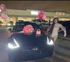 a woman standing next to a car with balloons on it