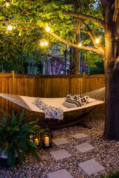 a hammock in the middle of a yard with lights strung up on it